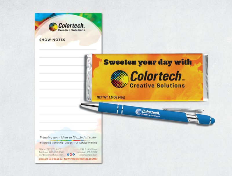 Colortech promotional items: a notepad, a chocolate bar, and a pen.