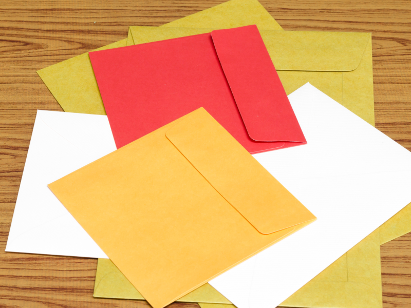 A stack of colorful announcement envelopes on top of a wooden table