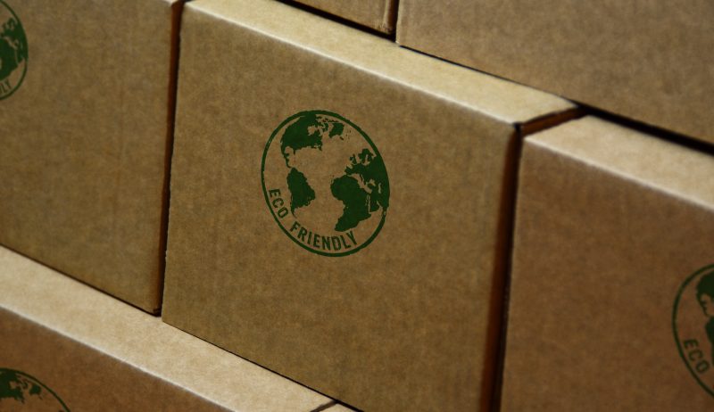 A drawing of a globe and "Eco Friendly" text on a box. Boxes are stacked on top of one another, but view only shows entirety of one box.